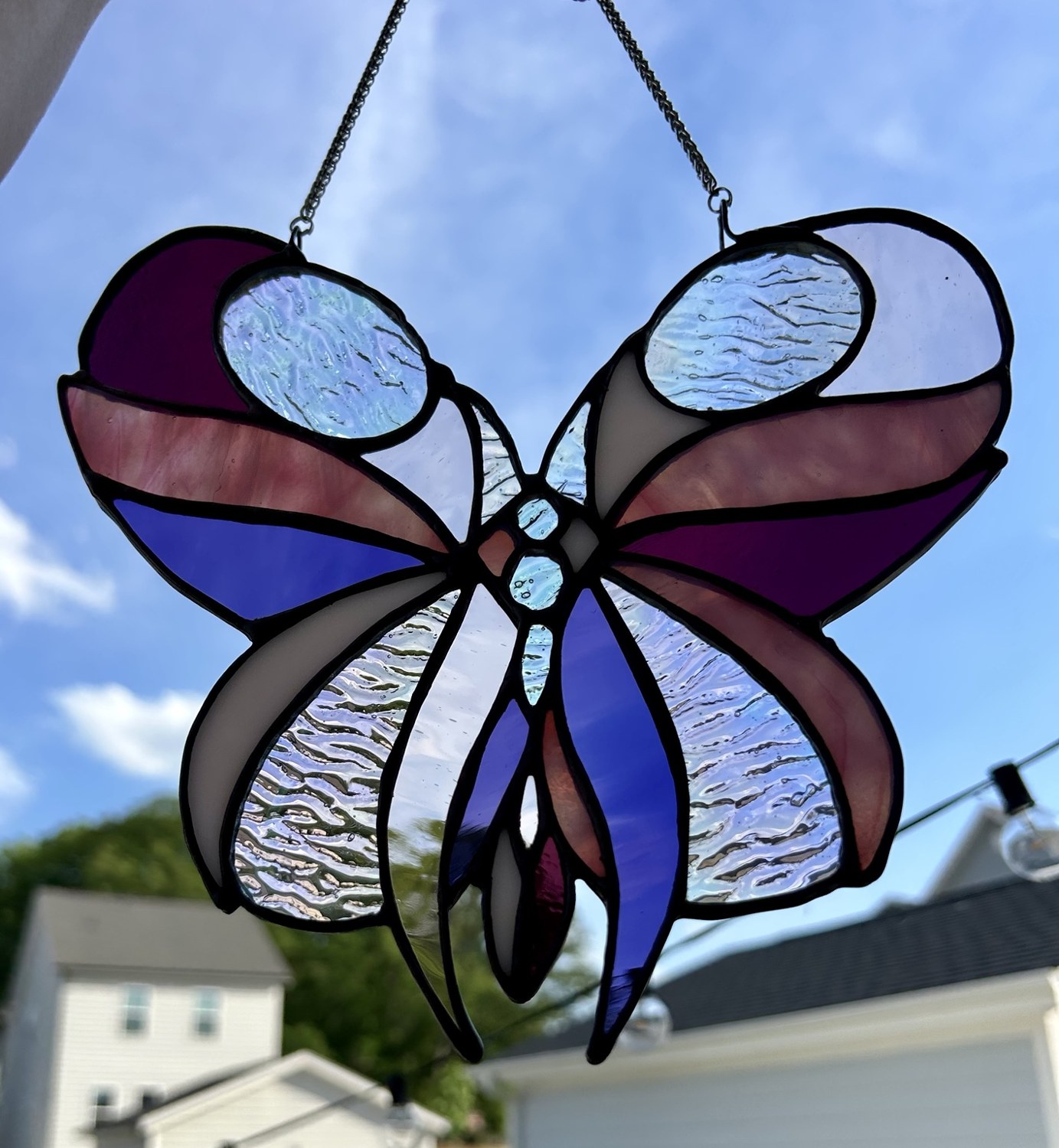 The same stained glass butterfly held against a bright blue sky