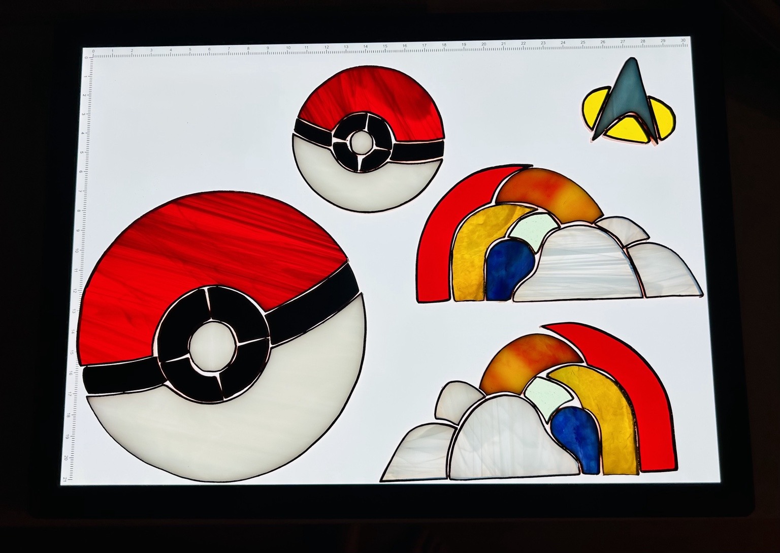 A workbench view of red-and-white circular designs, rainbows and a small space-inspired emblem before assembly.