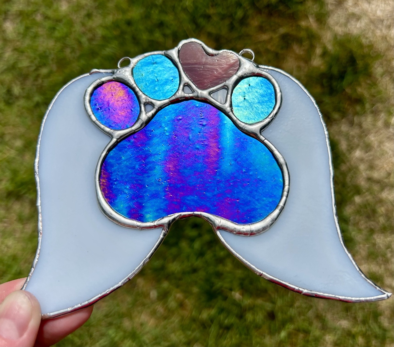 An iridescent blue paw with pale wings and a pink heart.