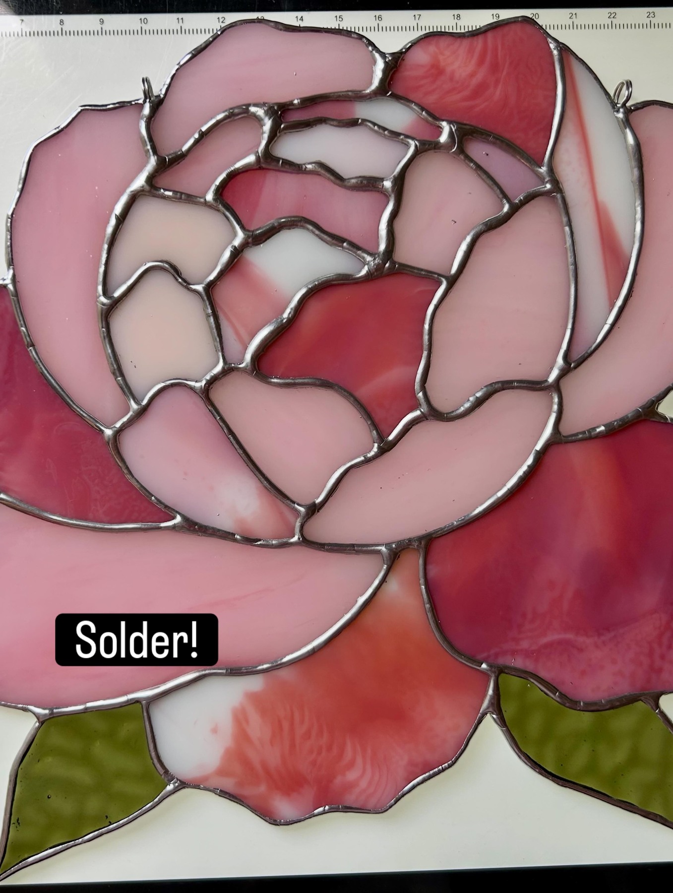 A closer view of the same peony, showing its soft colors and curved solder lines.