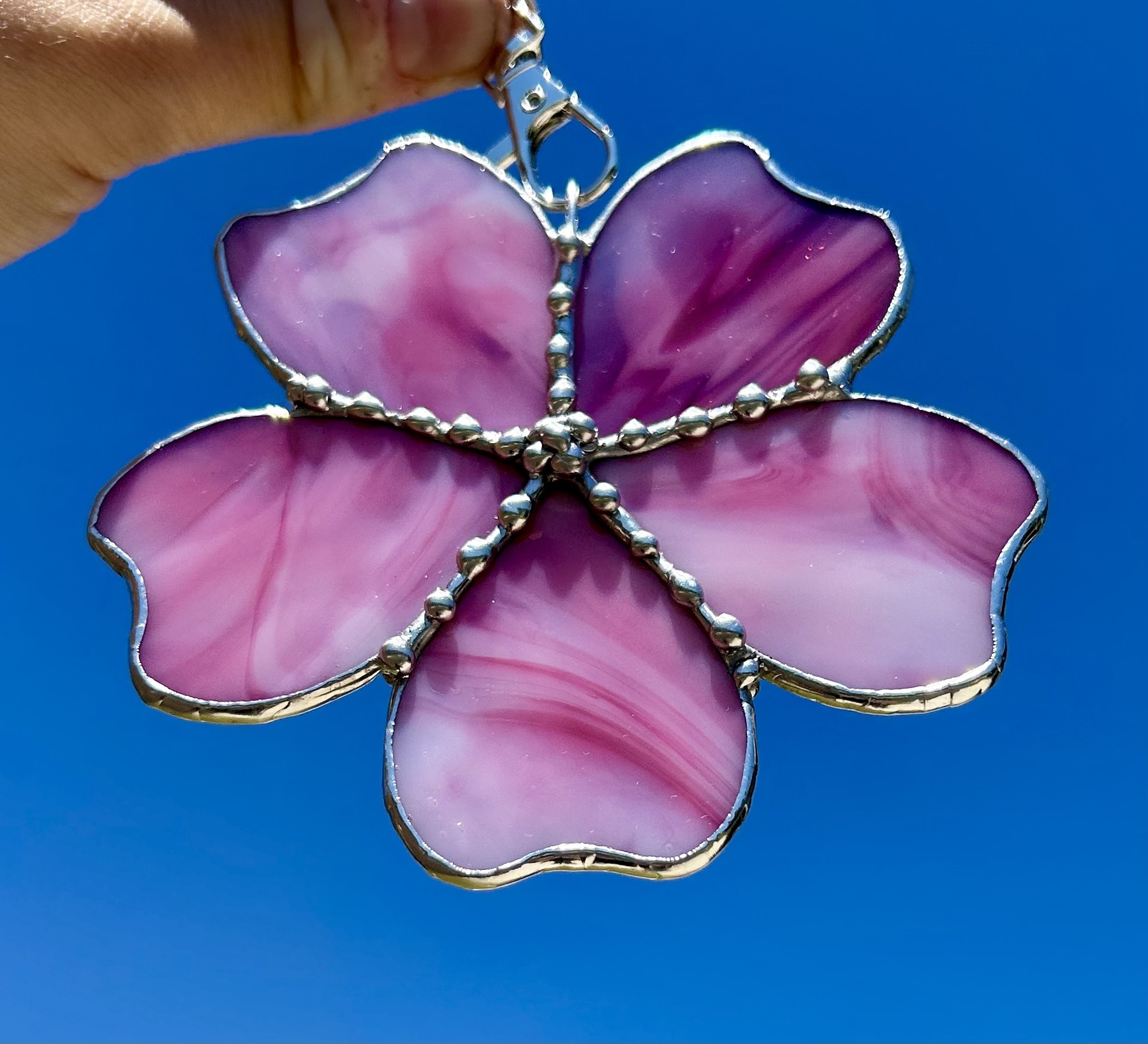 Five swirling pink petals edged with decorative solder details.