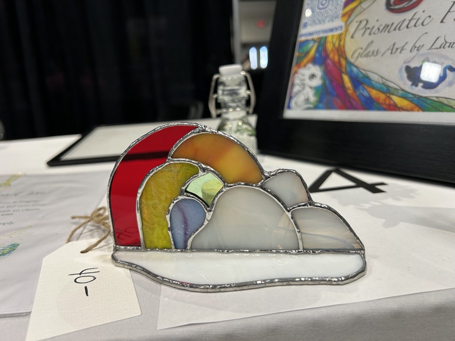 A rainbow and pale cloud paired with a small glass base.